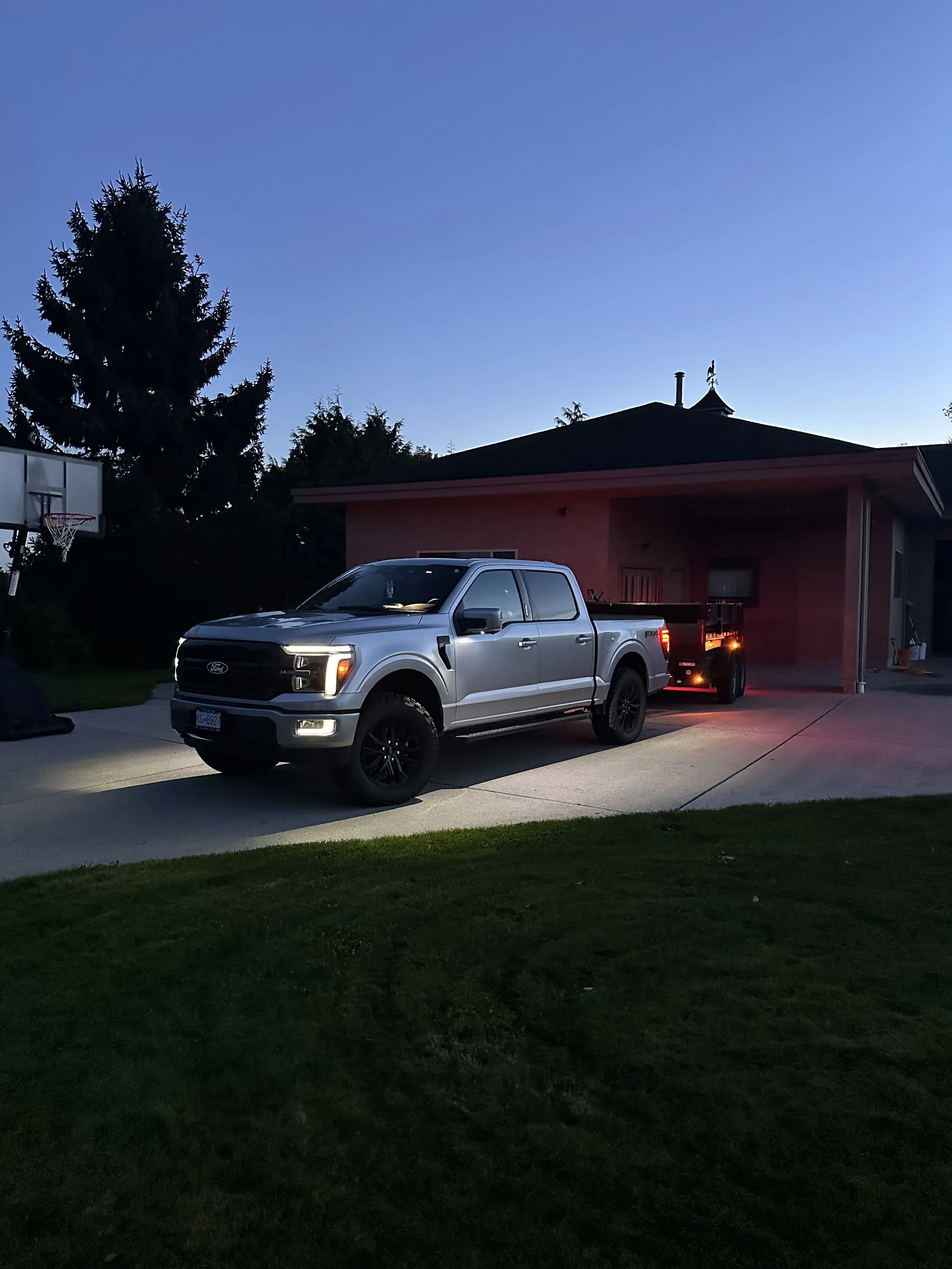 BRB's pickup and dump trailer parked in a client's driveway at dusk